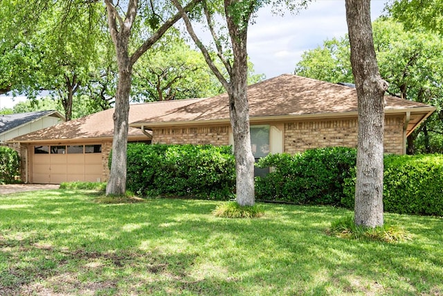 view of front facade with a garage, brick siding, a front yard, and roof with shingles