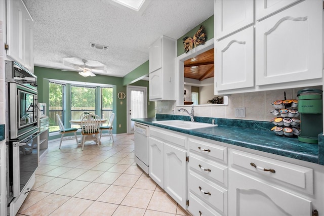kitchen featuring dark countertops, dishwasher, ceiling fan, and a sink