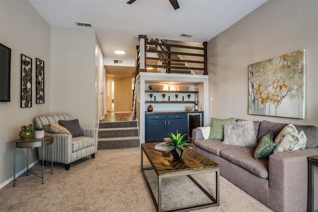 living room featuring visible vents, light colored carpet, beverage cooler, and indoor bar