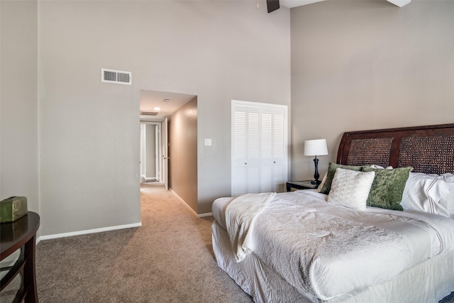 bedroom with visible vents, carpet, a towering ceiling, and baseboards