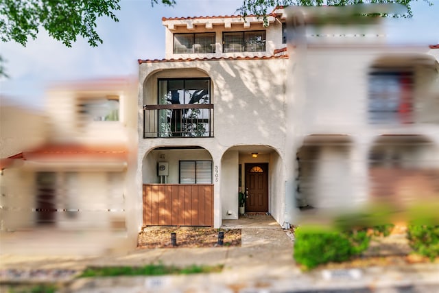 mediterranean / spanish-style house with stucco siding, a balcony, and a tile roof