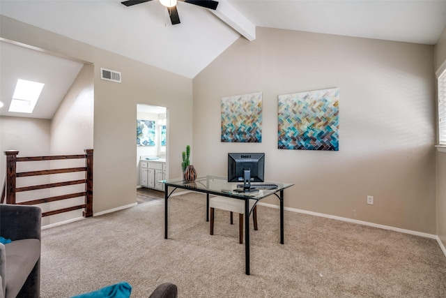 office area with a ceiling fan, visible vents, a skylight, beamed ceiling, and carpet