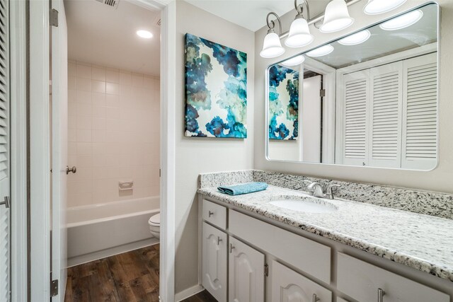 full bath featuring washtub / shower combination, vanity, toilet, wood finished floors, and visible vents