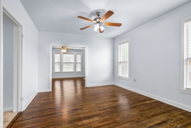 unfurnished room featuring dark wood finished floors, a ceiling fan, baseboards, and plenty of natural light