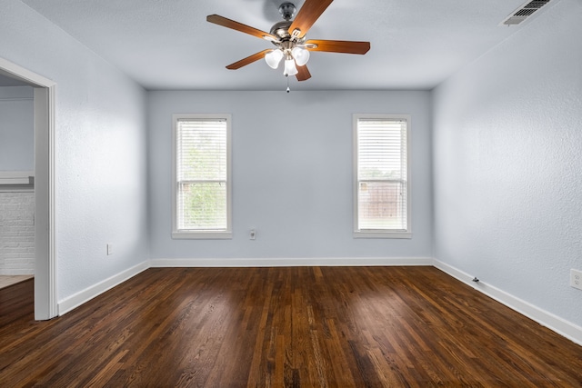 unfurnished room with baseboards, visible vents, a ceiling fan, and dark wood finished floors