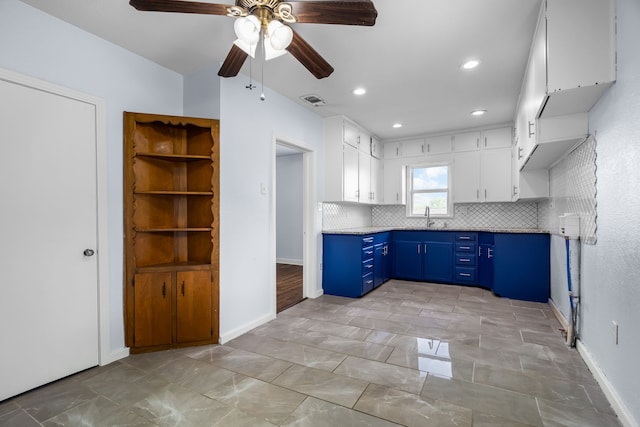 kitchen with blue cabinets, decorative backsplash, white cabinets, ceiling fan, and a sink