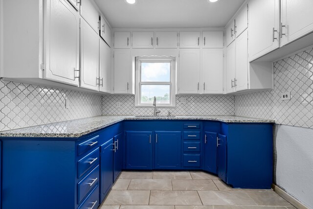 kitchen with decorative backsplash, white cabinets, and a sink