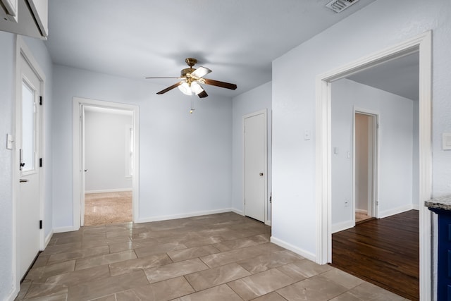 empty room featuring baseboards, visible vents, and ceiling fan