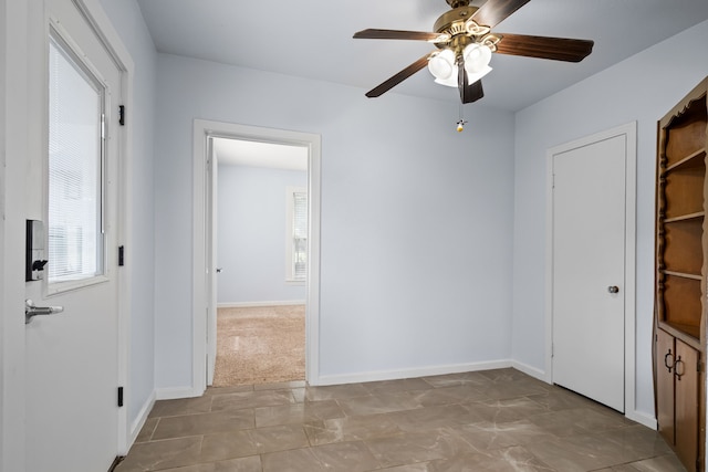 unfurnished room with ceiling fan and baseboards