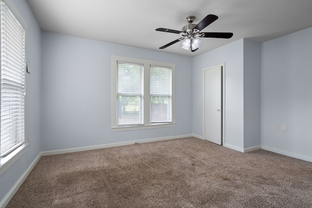 carpeted spare room featuring baseboards and ceiling fan