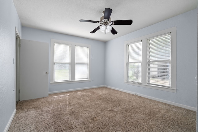 empty room featuring baseboards, a ceiling fan, and carpet
