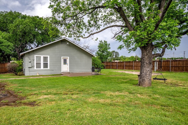 rear view of house featuring a yard, a fenced backyard, and a patio area