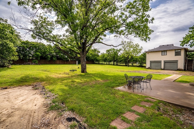 view of yard featuring an attached garage and a patio area