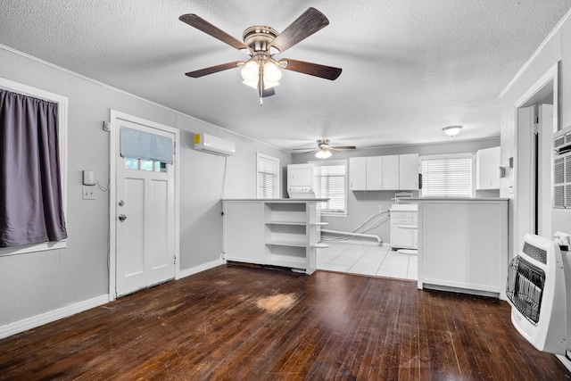 unfurnished living room with heating unit, ceiling fan, a textured ceiling, and a wall unit AC