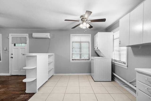 clothes washing area with stacked washer and clothes dryer, a ceiling fan, baseboards, a wall mounted air conditioner, and laundry area