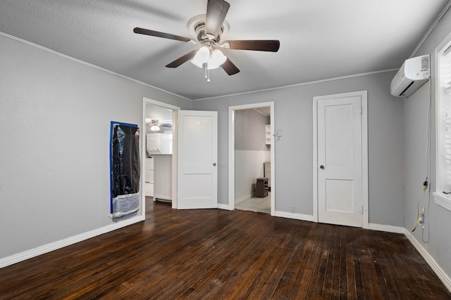 unfurnished bedroom with crown molding, a wall mounted AC, hardwood / wood-style flooring, and baseboards