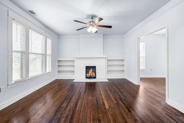 unfurnished living room featuring a brick fireplace, a wealth of natural light, wood finished floors, and baseboards