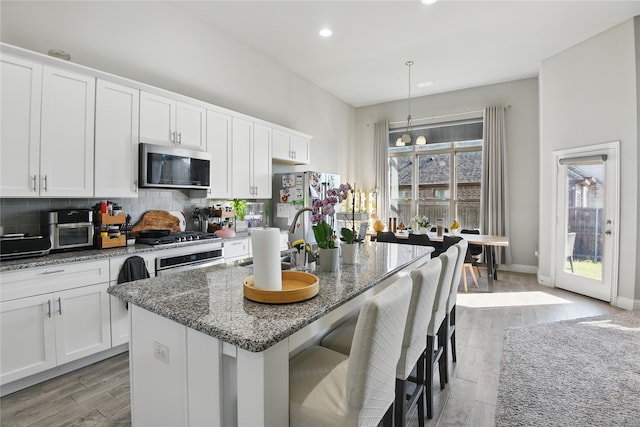 1164 Red Hawk Ln, Forney, TX 75126 - kitchen with dark stone counters, decorative backsplash, appliances with stainless steel finishes, wood tiled floor, and a kitchen island with sink