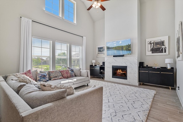 living area featuring light wood-type flooring, a wealth of natural light, a fireplace, and ceiling fan