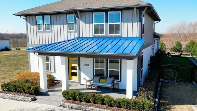 view of front of property featuring a porch, a standing seam roof, board and batten siding, and fence