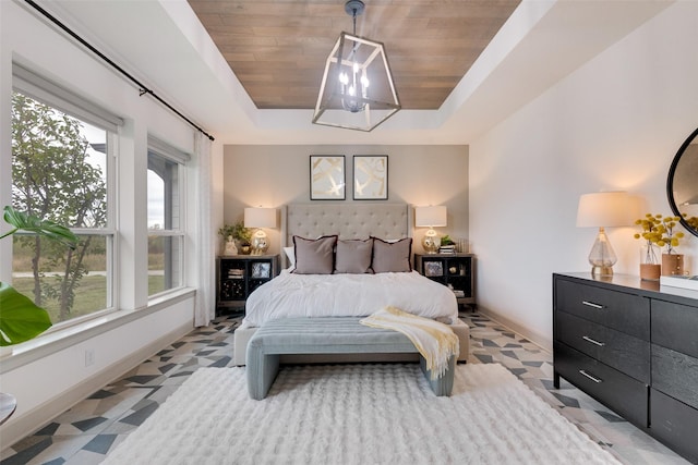 bedroom featuring a raised ceiling, light floors, and multiple windows