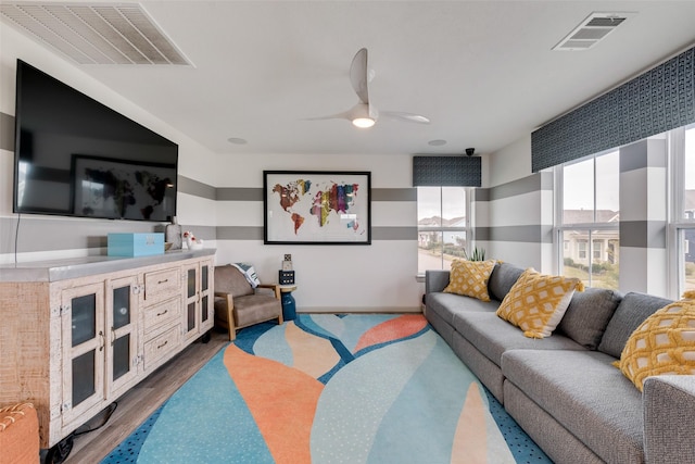 living area with a ceiling fan, visible vents, wood finished floors, and baseboards