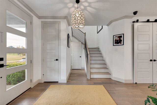 entryway with crown molding, stairs, wood finished floors, and baseboards