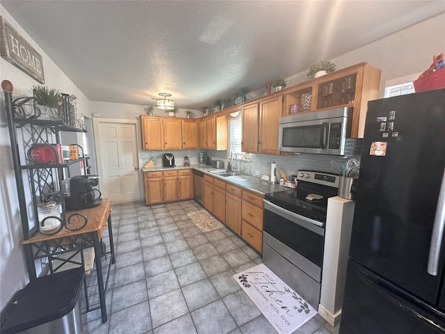 kitchen featuring a sink, stainless steel appliances, tasteful backsplash, light countertops, and a textured ceiling