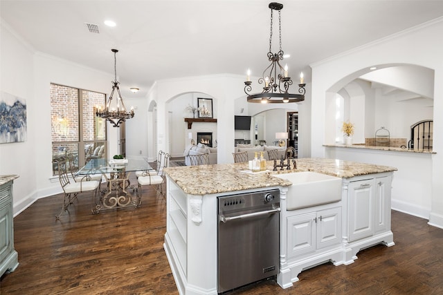 living area with a glass covered fireplace, a high ceiling, arched walkways, dark wood finished floors, and ceiling fan with notable chandelier