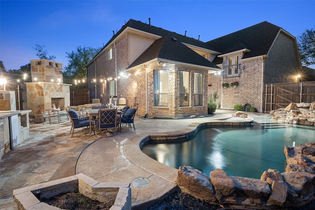 view of pool with an outdoor stone fireplace, fence, a patio area, and a fenced in pool