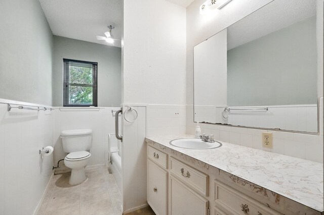 2134 Braune Rd, Abilene, TX 79606 - bathroom featuring toilet, vanity, a bathtub, wainscoting, and a ceiling fan