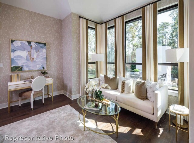 living area featuring wallpapered walls, a wealth of natural light, wood finished floors, and baseboards
