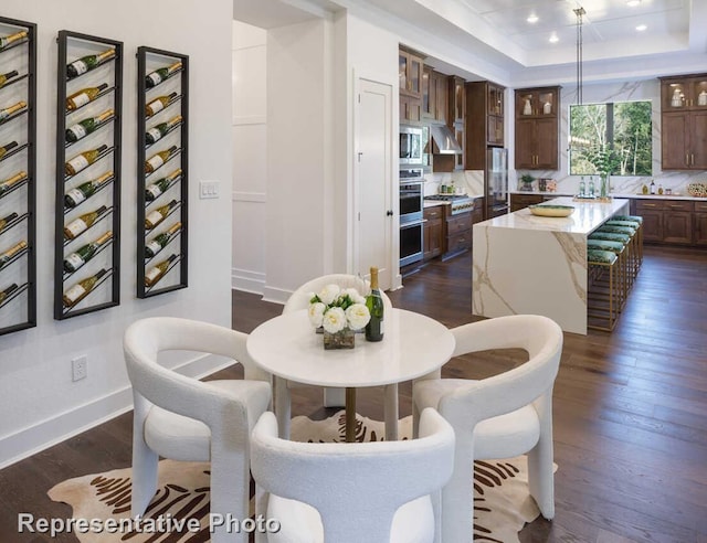 dining area with recessed lighting, baseboards, a raised ceiling, and dark wood finished floors