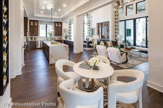 dining space with dark wood-style flooring, a raised ceiling, recessed lighting, and baseboards