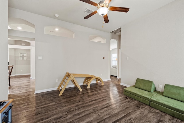 living room featuring arched walkways, a ceiling fan, wood finished floors, and visible vents