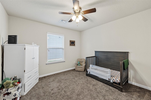 bedroom with ceiling fan, visible vents, a crib, and carpet