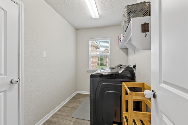 laundry room featuring laundry area, baseboards, a textured ceiling, light wood finished floors, and independent washer and dryer