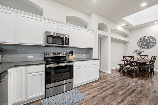 3017 Gilchrist Dr, Waco, TX 76655 - kitchen featuring wood finished floors, dark countertops, stainless steel appliances, a skylight, and white cabinetry