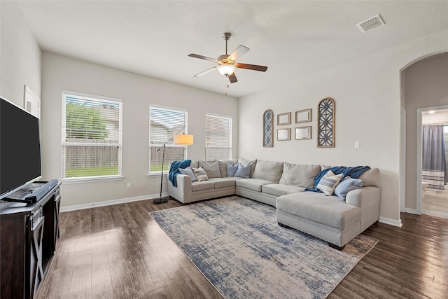 living room with arched walkways, ceiling fan, wood finished floors, and visible vents