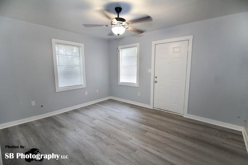 unfurnished room featuring baseboards, ceiling fan, and dark wood-style flooring