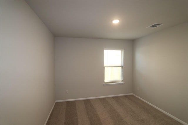 empty room featuring carpet flooring, visible vents, and baseboards