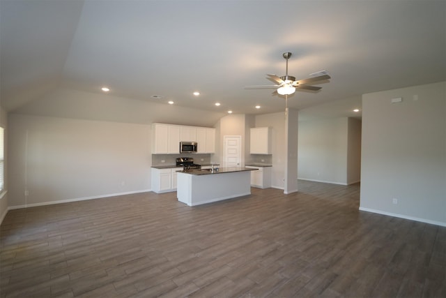 kitchen featuring appliances with stainless steel finishes, open floor plan, dark countertops, and dark wood finished floors