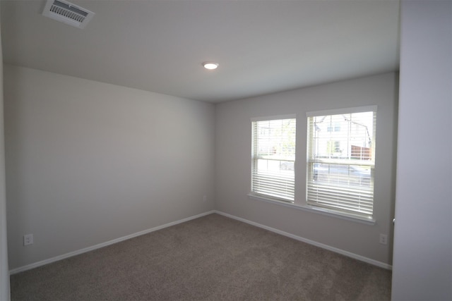 carpeted spare room with visible vents and baseboards