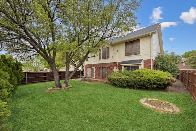 back of property with a lawn, a fenced backyard, and brick siding