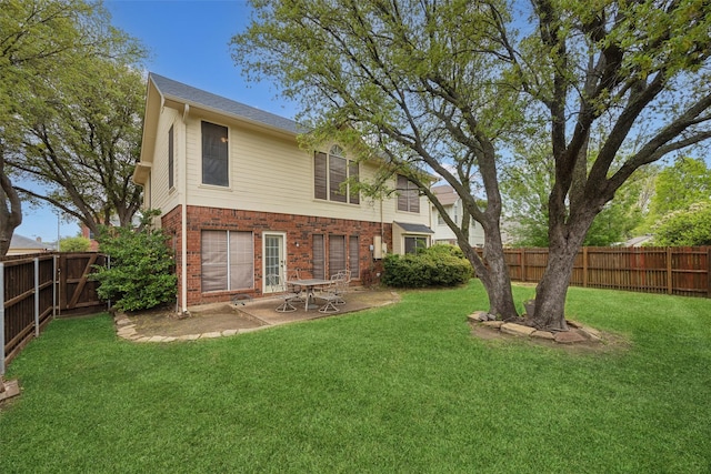rear view of property with a lawn, a patio, a fenced backyard, and brick siding