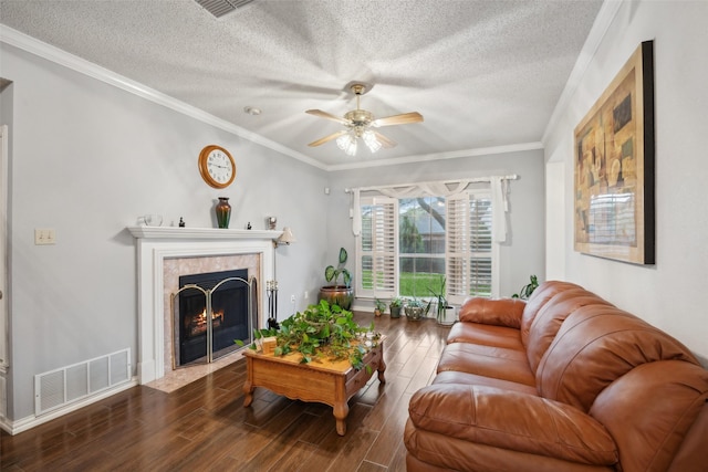 living area with a textured ceiling, visible vents, ceiling fan, a tile fireplace, and wood finished floors