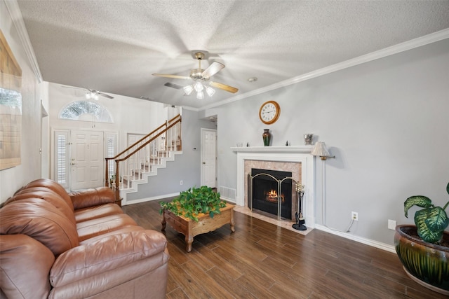 living area with stairway, a tiled fireplace, ceiling fan, a textured ceiling, and wood finished floors
