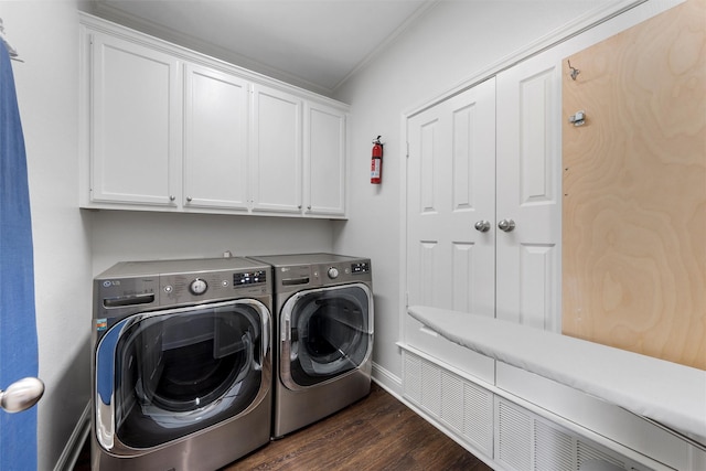 laundry room featuring crown molding, washing machine and clothes dryer, baseboards, cabinet space, and dark wood finished floors