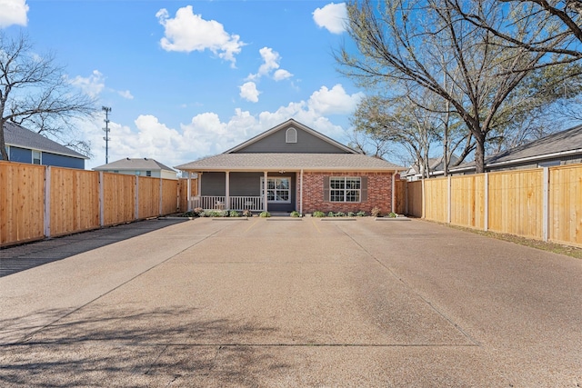 view of front of property with covered porch, brick siding, and fence