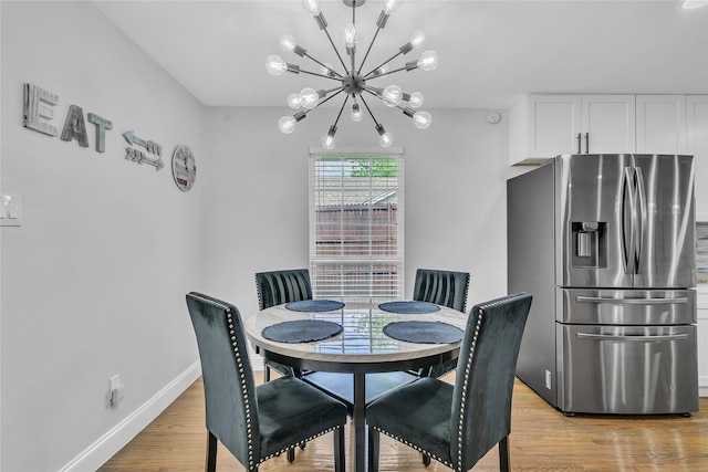 dining area featuring a chandelier, baseboards, and light wood-style floors